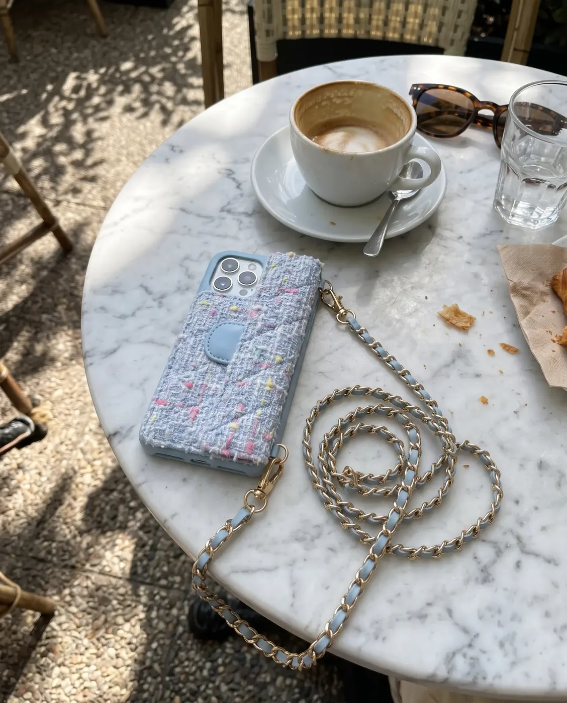 Sky Blue Tweed phone purse with a full-length pocket on a café table with a latte, sunglasses and a glass of water
