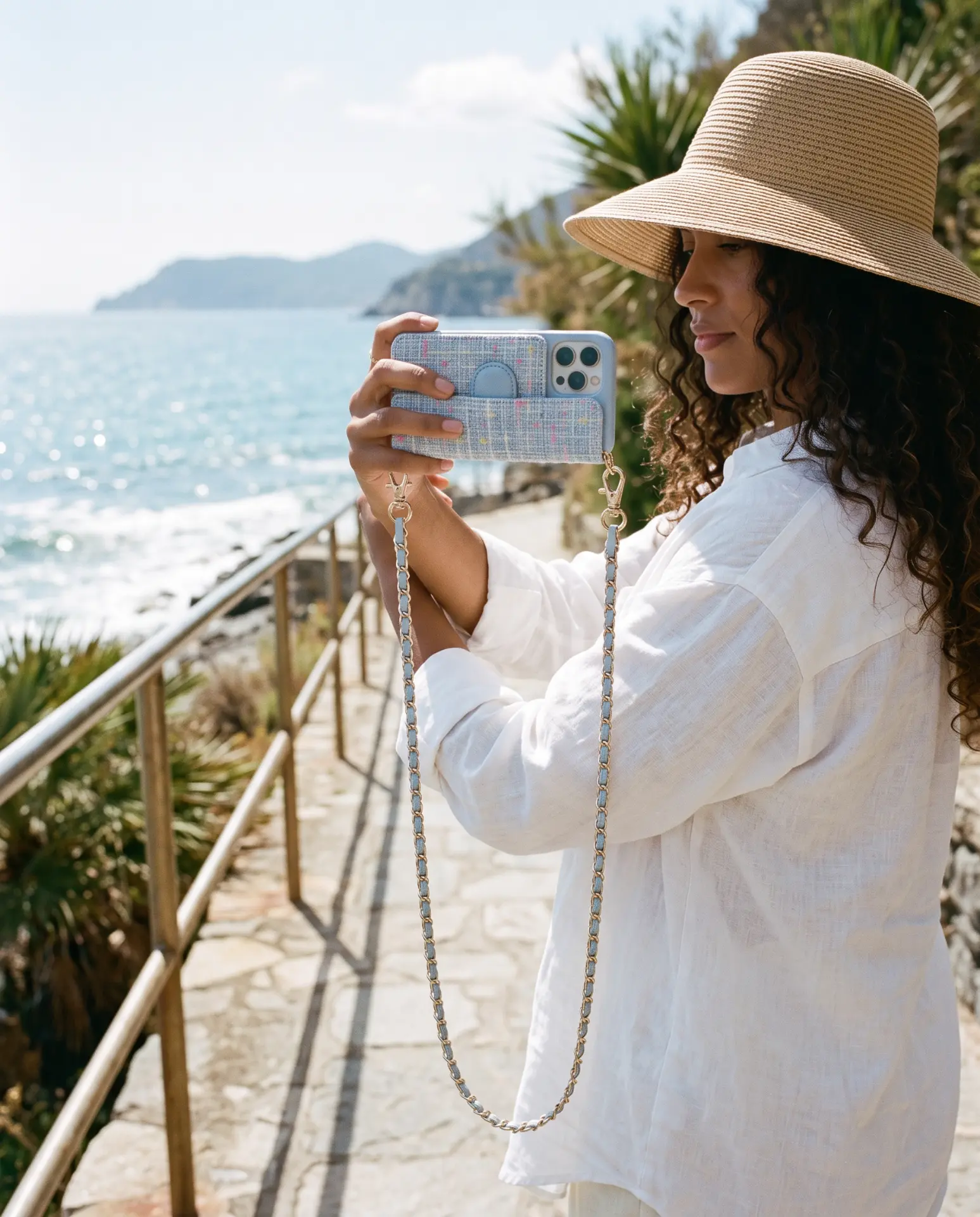 Sky Blue Tweed phone purse with a full-length pocket held up to photograph the sea from a coastal path