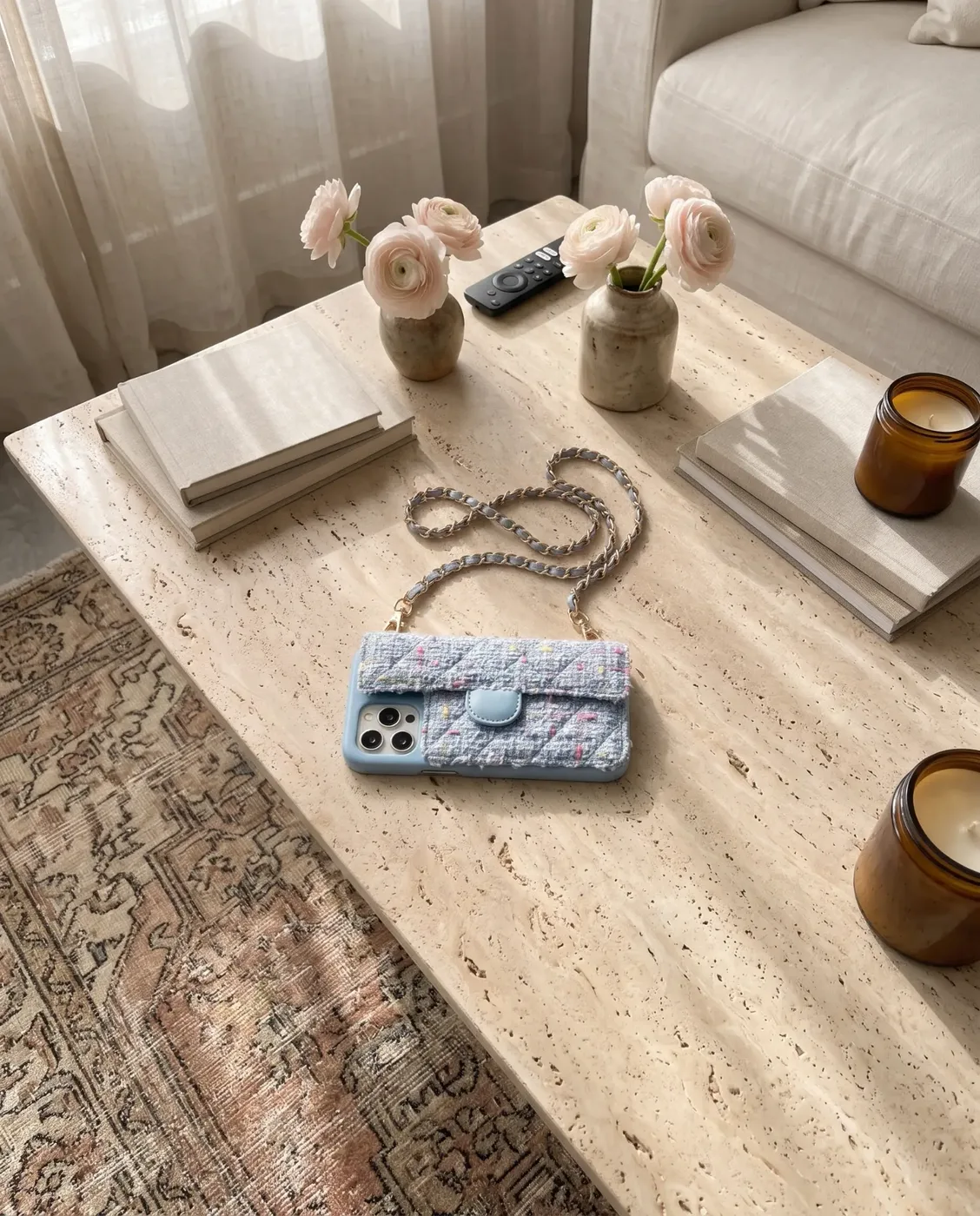 Sky Blue Tweed phone purse with a full-length pocket on a travertine table with books and pink flowers