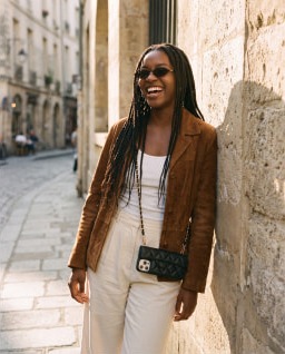 A black phone purse worn crossbody on a cobbled street